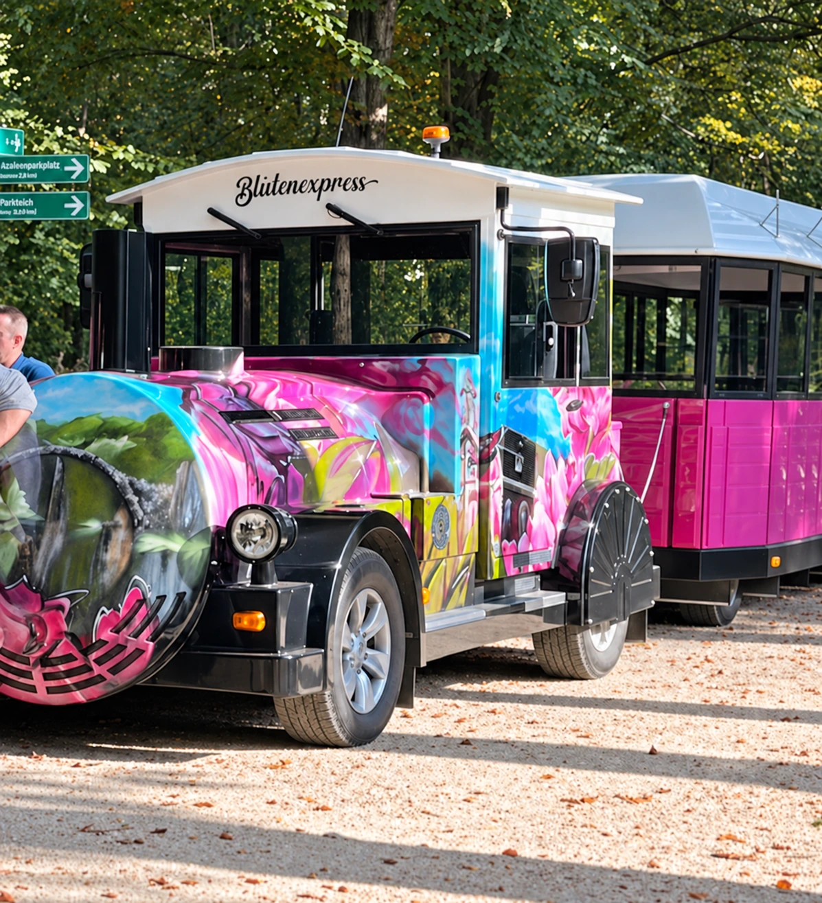 Der Kromlauer Blütenexpress mit farbig gestalteter Zugmaschine und Personenanhänger